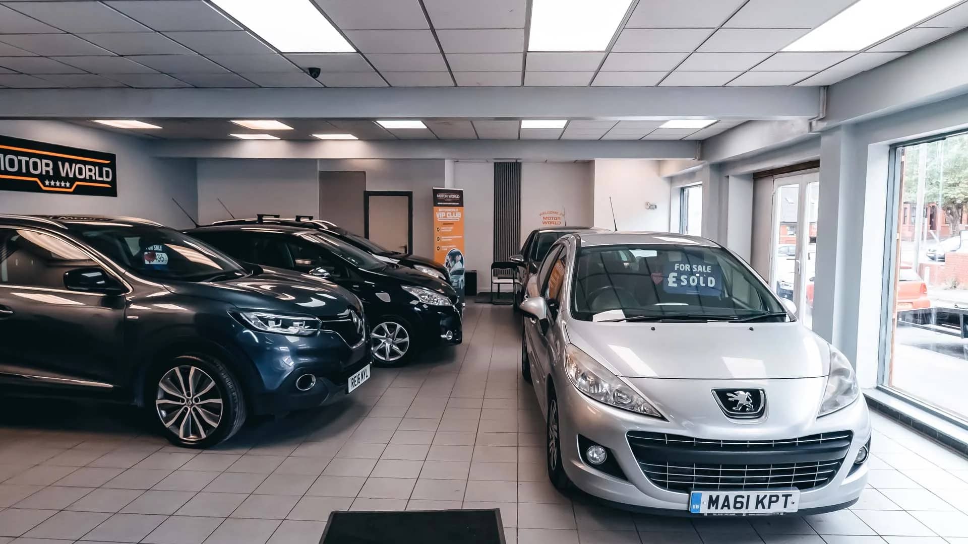 Inside the MotorWorld showroom with used cars lined up and MotorWorld branding on the wall