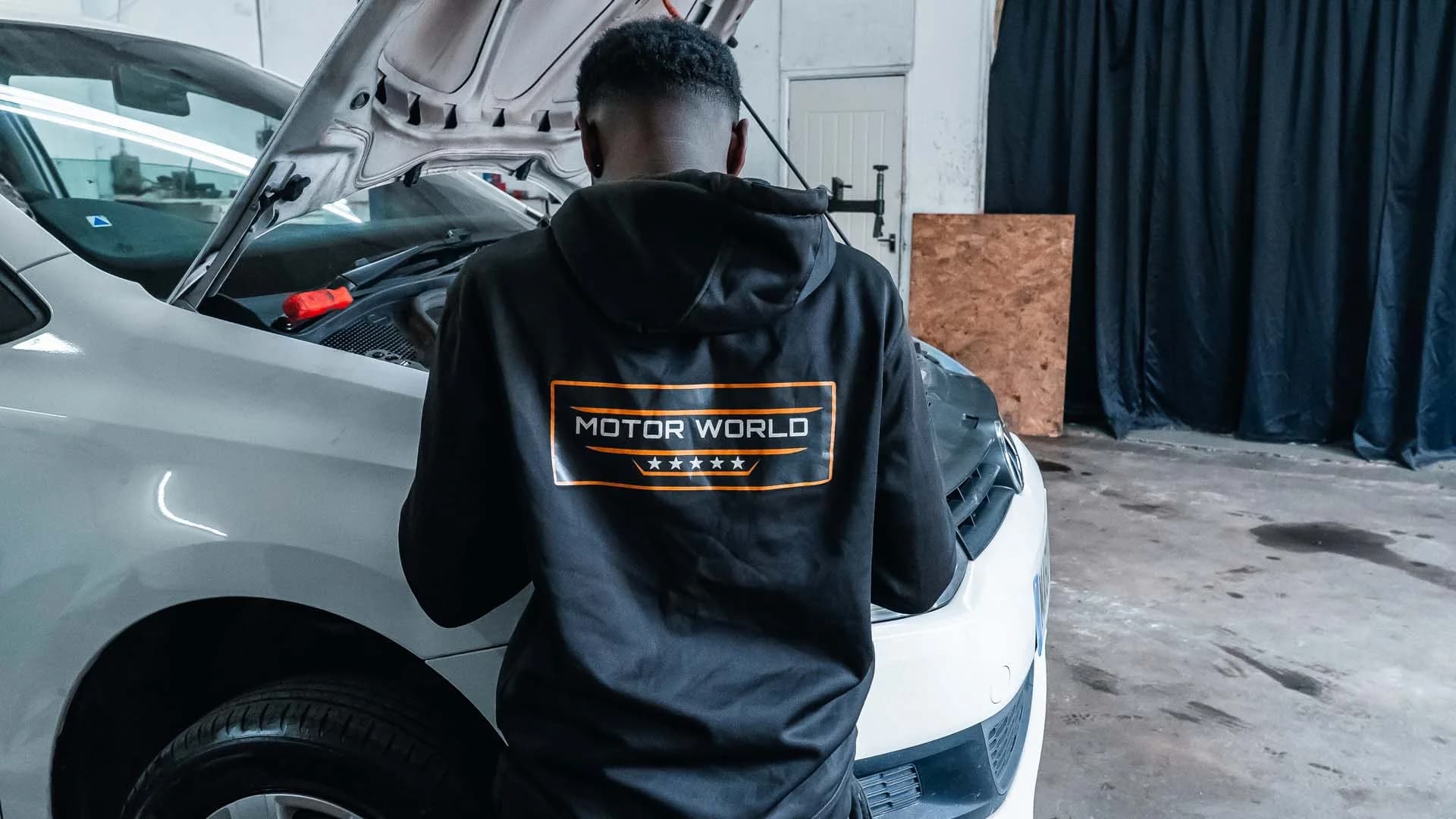 MotorWorld technician working on a car with the bonnet open
