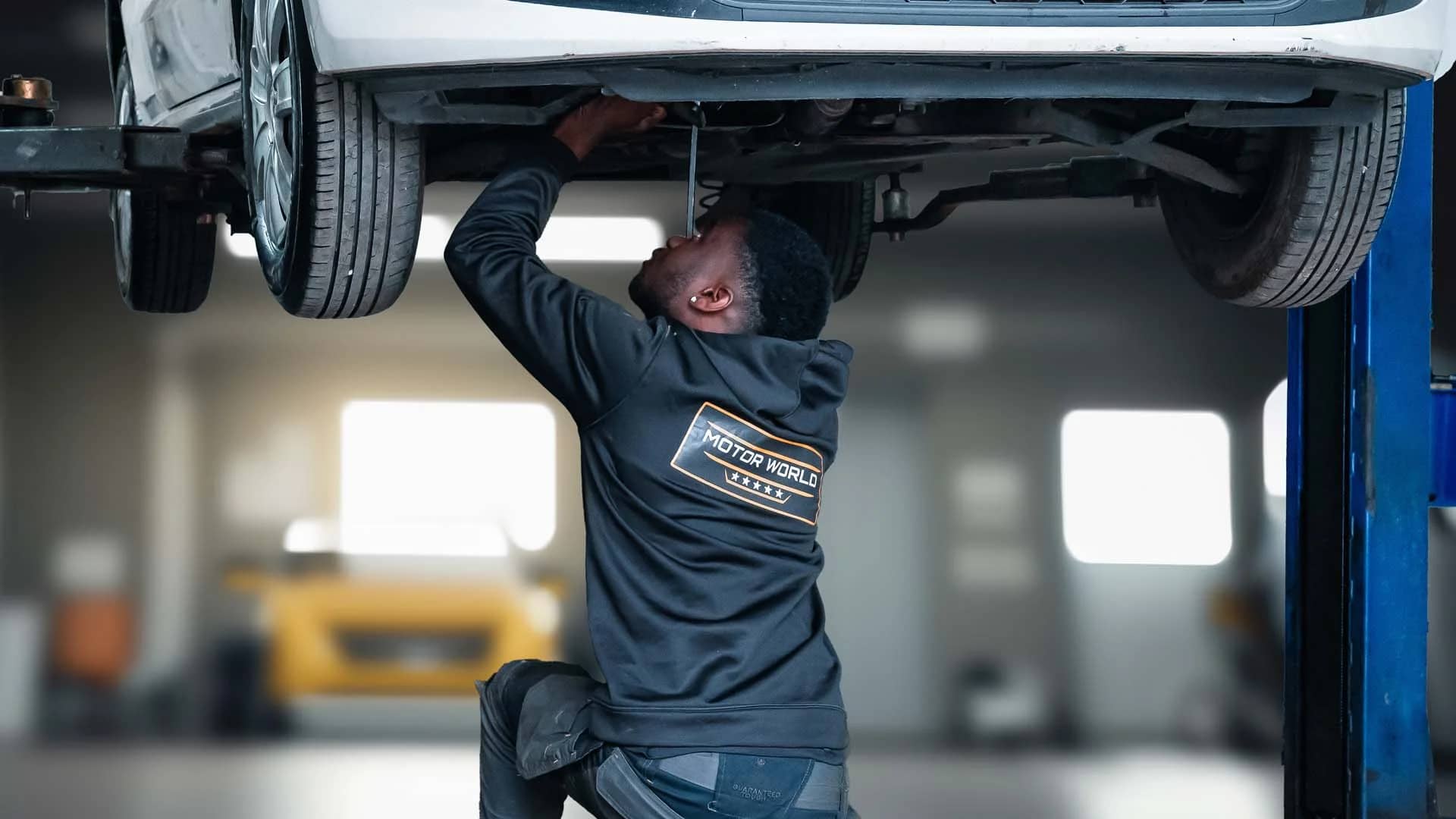 MotorWorld technician working on a car raised on the MOT bay ramp